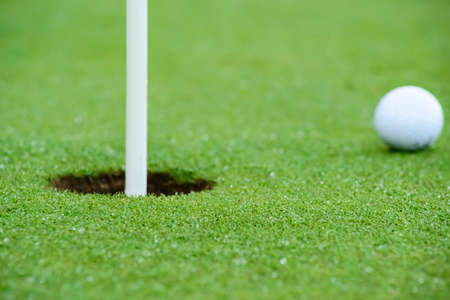 Horizontal photography with a great blur where only the hole comes out in focus and it looks like the ball is about to enter the holeの写真素材