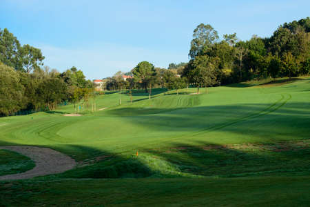 horizontal photograph of a fairway on a golf course even with dew, differentiate the fairway, the rough, even the green flagの写真素材