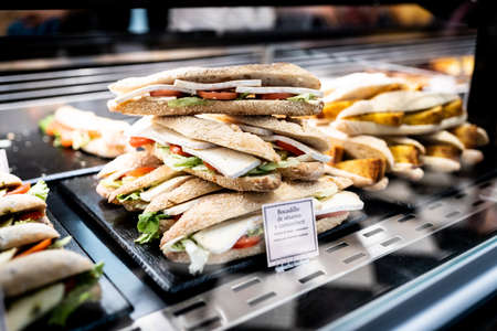 Assortment of cheese sandwiches in the display window of a food storeの写真素材