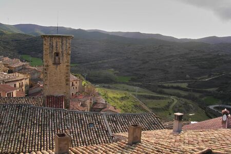 Medieval tower in rustic town, landscape with green meadows and blue sky