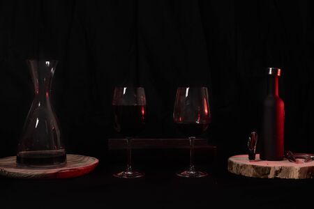 Wine glasses with bottle and pourer. Two wine glasses with wine utensils for the bottle, bottle and decorations, dark and blackの写真素材