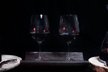 Two wine glasses filled on top of a tile, On a black background and utensils for wine. Dark and blackの写真素材