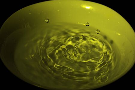 Drop of water on white bowl, yellow, black backgroundの写真素材