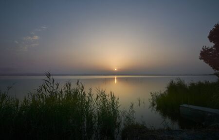 Sunset on the big lake, from the reeds, green, golden colors, calm waters, reflections, long expositionの写真素材