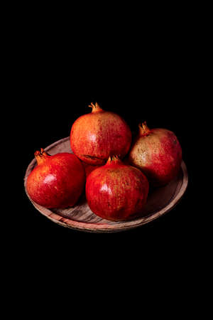 Pomegranates on wooden plate, Black background, macro photographyの写真素材