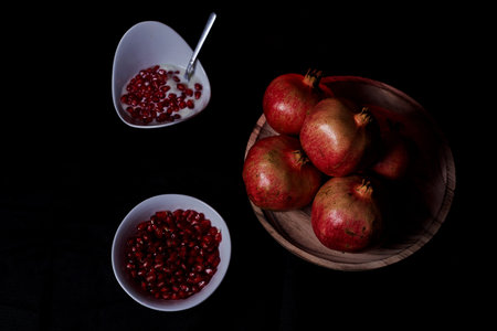 Pomegranates in table and seeds in bowl with yogurt, Black background, macro photography