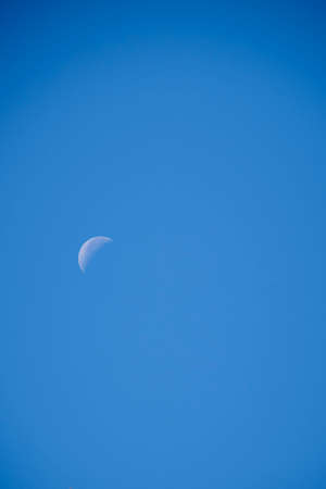Crescent moon over cloudless, blue, blue sky, sunnyの写真素材