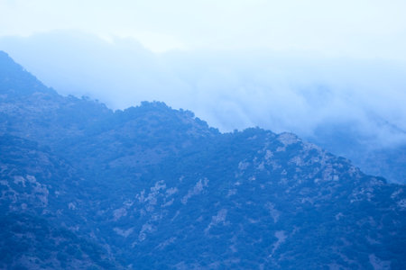 High mountains surrounded by clouds and forests, blue, storm, cold