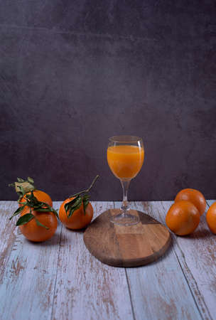 Glass of orange juice on wooden table with various oranges marble background wooden floorの写真素材