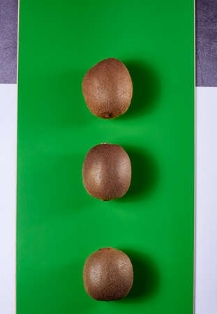 Three kiwis on green background, wood, white background and stone, zenithal viewの写真素材