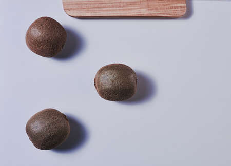 Three kiwis on a wooden board. Clean white background, zenithal view, empty space.の写真素材