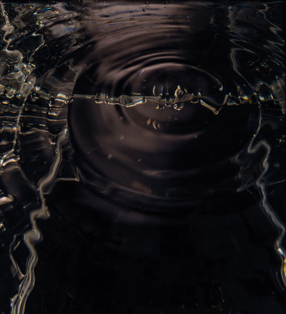 463.Close-up of water surface showing concentric ripple rings and low-light reflections.Lighting creates abstract texture and motion. Image captures fluid dynamics, surface tension, and wave behavior.の写真素材