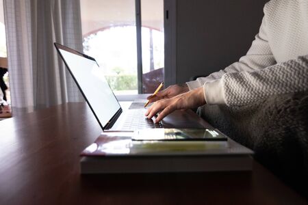 hands working with computer sitting on sofa at homeの写真素材