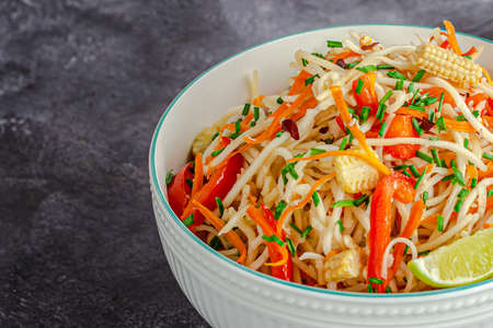 Vegetable Chow Mein with Bell Pepper, Baby Corn, Carrot Garnished with Chives and Lemonの写真素材