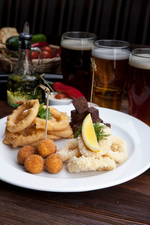 plate with beer snacks, fried croutons, squid, onions and saucesの写真素材