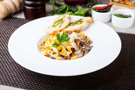 Italian pasta with meat in mushroom sauce and toast with pesto sauceの写真素材