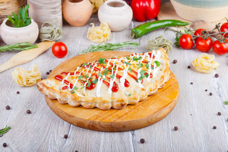 pizza calzone with red and white sauce on a wooden boardの写真素材