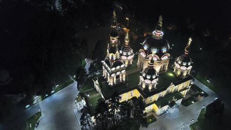Bright Church with golden domes and crosses. Glows in the night Park. Drone footage. Top and side view. Evening Cathedral in the Park. Bright temple. Modern design of the old building. Lots of lights.の写真素材