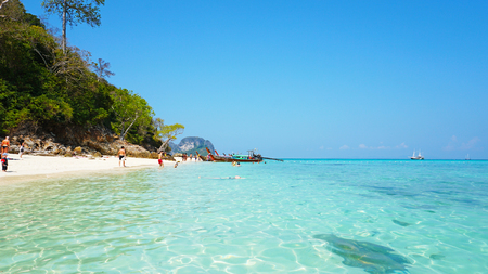Beautiful beach, clear water and white sand. People relax on the beach. Paradise island. You can see the bottom through the water. Green trees, palm trees. Tourist vacation. Phi Phi Islands, Thailand.のeditorial素材