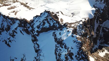 View of the snowy peaks from the drone. Highest peak. You can see huge rocks, cliffs, avalanches, and the shadow falls on them. At an altitude of more than 4300 meters. Mountains Of TRANS-Ili Alatau.の写真素材