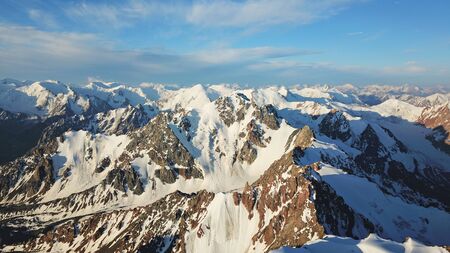 View of the snowy peaks from the drone. Highest peak. You can see huge rocks, cliffs, avalanches, and the shadow falls on them. At an altitude of more than 4300 meters. Mountains Of TRANS-Ili Alatau.の写真素材