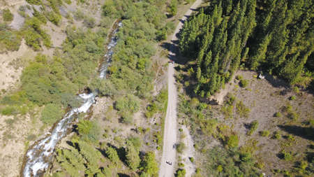 View of the forest and gorge from above. Huge rocks of the gorge covered with coniferous trees. You can see paths and people walking along them. The river runs. Mountainous area of Kazakhstan.の写真素材