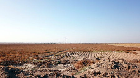 Windmills near the field. Top view from a drone. Blue sky, light shroud, windmills turn, green...