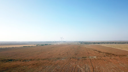 Windmills near the field. Top view from a drone. Blue sky, light shroud, windmills turn, green...