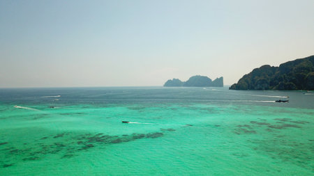 Turquoise clear water. Yachts, boats floating. Water Gradient from light to dark blue. Phi Phi don island, shooting from a drone from the air. White sand, green trees, palm trees and large hills.の写真素材