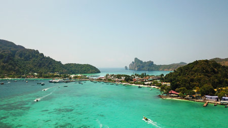 Turquoise clear water. Yachts, boats floating. Water Gradient from light to dark blue. Phi Phi don island, shooting from a drone from the air. White sand, green trees, palm trees and large hills.の写真素材