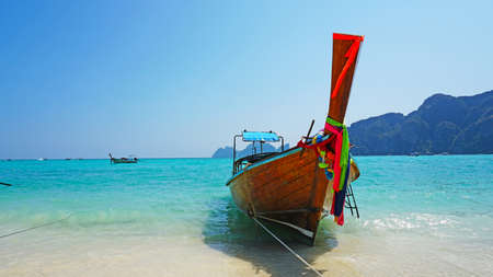 Sea long-tailed boats. Traditional Thai boats. Bright colored ribbons. Turquoise, blue, clear water. White sand on the beach. Holiday boat. A small wave. Travel to Asia. The Island Of Phi Phi Don.の写真素材