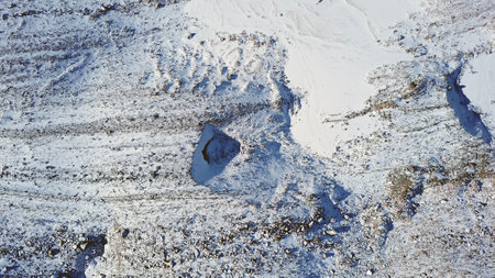 Entrance to an ice cave in the mountains. Tuyuk Su Glacier, all covered in white snow. You can see an ice grotto covered with ice and rocks. High rocks and mountains. The entrance looks like a dolphinの写真素材
