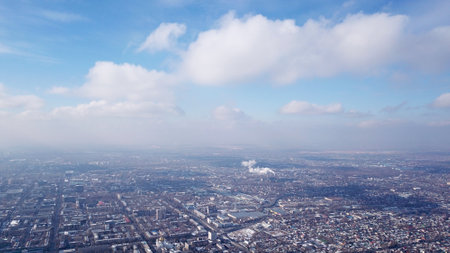 Winter in the city of Almaty in smog. Top view from a drone. A gray haze hangs over the city. In the distance, you can see the smoky chimneys of the factory. Blue sky with white clouds. Kazakhstanの写真素材
