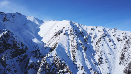 Huge rocks covered with snow. Dangerous terrain. High mountains, cliffs, and large rocks. Shadow from the suns rays. Top and side view from the drone. An epic place. The Mountains Of Almaty.の写真素材