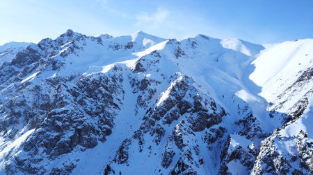 Huge rocks covered with snow. Dangerous terrain. High mountains, cliffs, and large rocks. Shadow from the suns rays. Top and side view from the drone. An epic place. The Mountains Of Almaty.の写真素材
