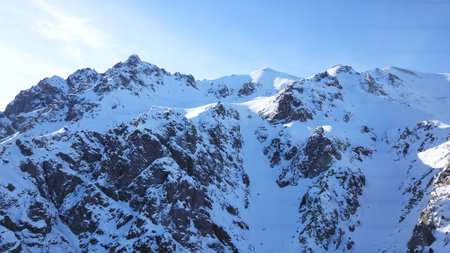 Huge rocks covered with snow. Dangerous terrain. High mountains, cliffs, and large rocks. Shadow from the suns rays. Top and side view from the drone. An epic place. The Mountains Of Almaty.の写真素材