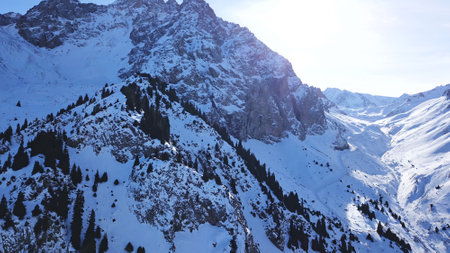 Huge rocks covered with snow. Dangerous terrain. High mountains, cliffs, and large rocks. Shadow from the suns rays. Top and side view from the drone. An epic place. The Mountains Of Almaty.の写真素材