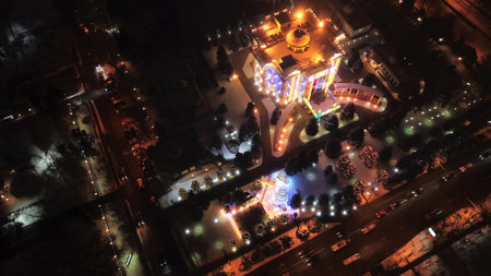 The city is decorated for Christmas and new year. Buildings, garlands, Christmas trees, fences and the square glow with different lights. People relax, enjoy the winter and holiday. View from a droneの写真素材