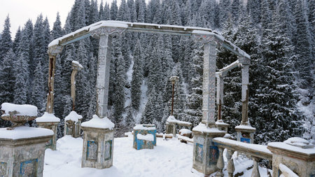 An old abandoned gazebo with views of the snowy mountains and forest. Clouds float beautifully, fir trees are covered with snow. High white hills. The stone pillars of the building are destroyed.の写真素材