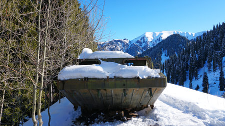Abandoned military vehicles in the snowy mountains. Retro off-road machine military years. Machine in the mountains and forest. Blue sky and shadows. Abandoned tank on top of a hill.の写真素材