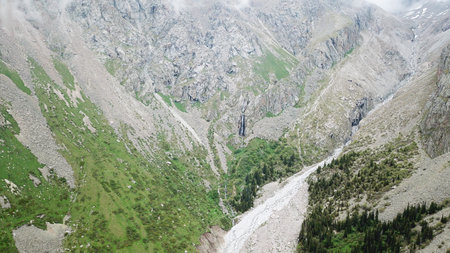 High waterfall among the rocks. View from a drone. Large rocks and steep slopes surround the...
