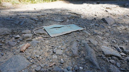 The medical mask is lying on the ground. An old used mask is lying dirty on the ground.の写真素材