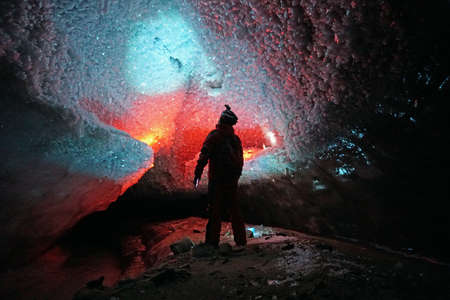 A guy in an ice cave with a lantern light.の写真素材