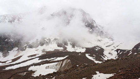 White clouds and snowy peaks. A lot of big stonesの写真素材