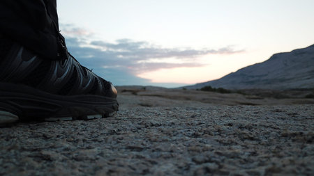 Mens legs in sneakers in the mountains.