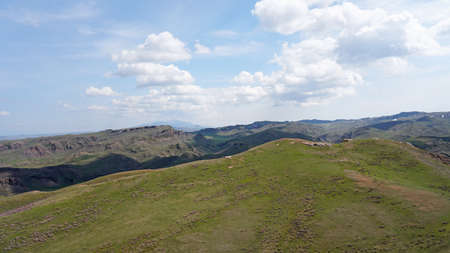 The shadow of the clouds runs over the green hillsの写真素材