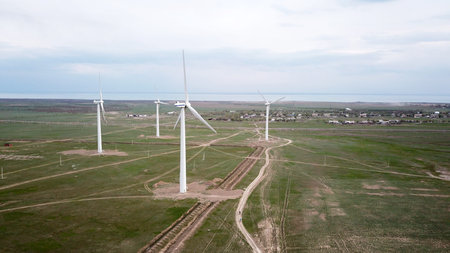 A group of cyclists rides along the windmills.