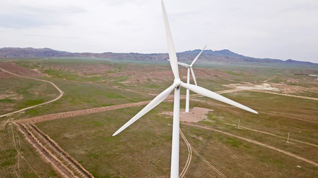 Windmills stand in the middle of green fields.