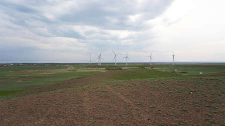 Windmills stand in the middle of green fields.の写真素材