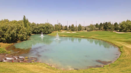 A beautiful pond with a fountain on golf courseの写真素材